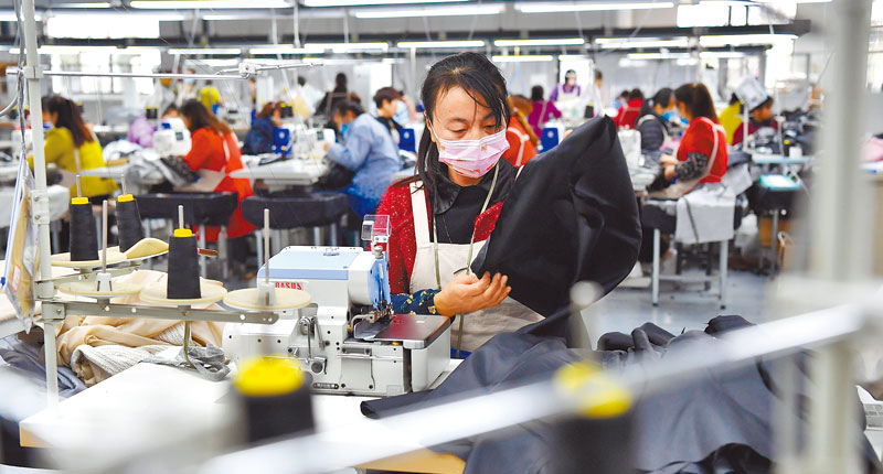 10月25日,陜西城固县产业发展助脱贫,工人在服饰公司生产线加工服装.