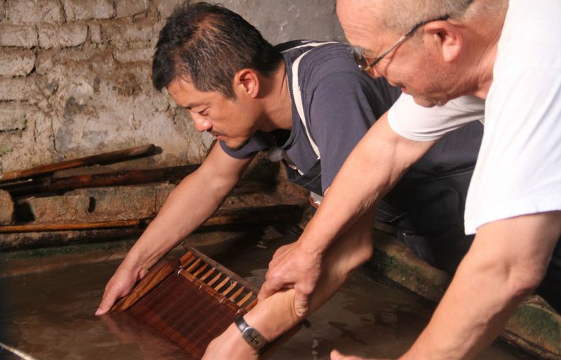 李亞鵬(左)在《百心百匠》中,和張逢學老人學習抄紙。(取自豆瓣網)