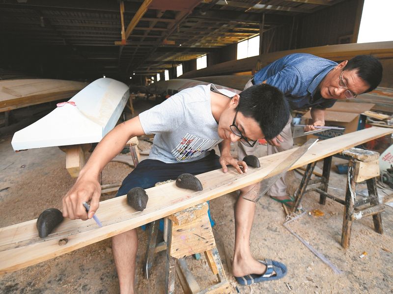 福建閩侯縣「龍舟世家」傳承人方劍偉向老一輩學習在木板上設計龍舟圖。(中新社)