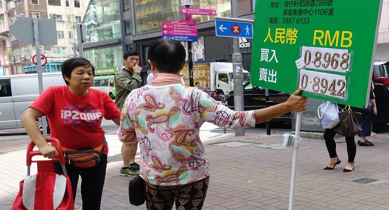 5年多,人行首次發行央票。圖為10月31日,外幣兌換店職員在香港灣仔街頭舉牌招攬顧客。(中新社)