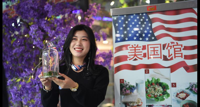 ▲2月22日,重慶保稅港區「一帶一路」沿線國家特色商品貿易及文化周啟動。圖為美國館工作人員展示該館特色產品。(中新社)