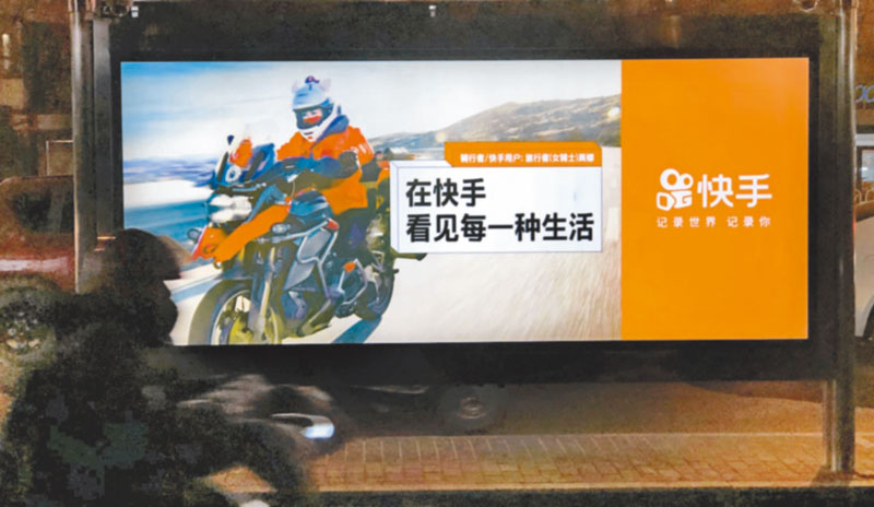 北京騎士經過公車站的「快手」廣告牌。(CFP)