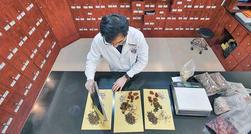 台灣青年就讀廣州中醫藥大學博士班,課餘之際,在工作的診所為顧客抓藥。 (新華社資料照片)