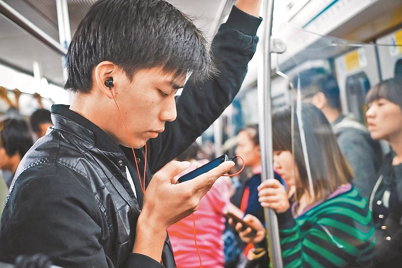 更多生活消費在手機上完成,卻很少有人認真去比較代價的差別。圖為一年輕人在北京地鐵上使用手機。(新華社資料照片)