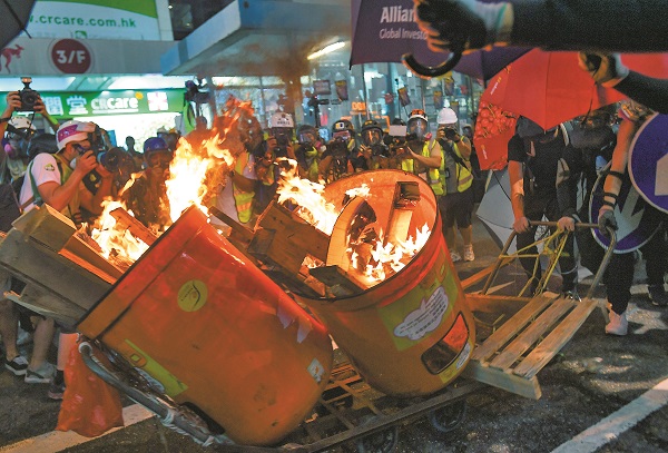 8月4日,香港銅鑼灣,示威者燃燒手推車上的垃圾筒和紙皮雜物。(中新社)