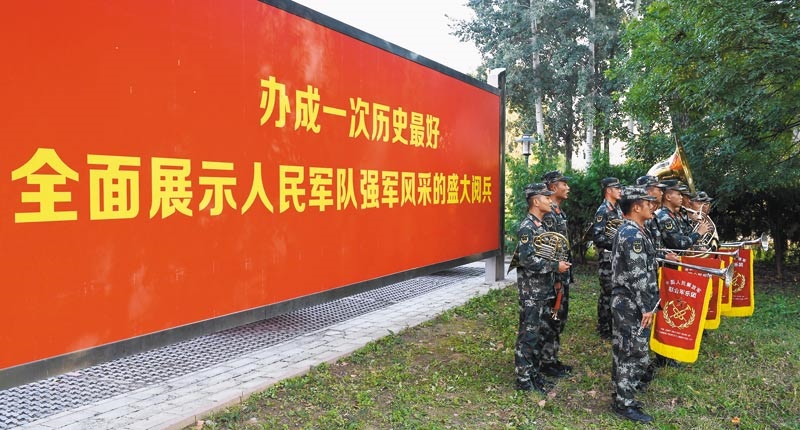 解放軍聯合軍樂團演奏員在訓練現場的一處標語前合影。(中新社)