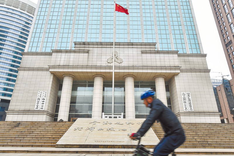民眾在中國人民銀行海口中心支行前經過。(中新社)