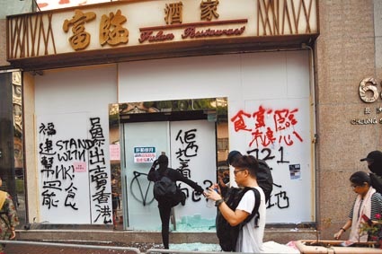 香港示威者12日在長沙灣道貿易廣場富臨酒家塗鴉及破壞,大門玻璃散落一地。(中新社)