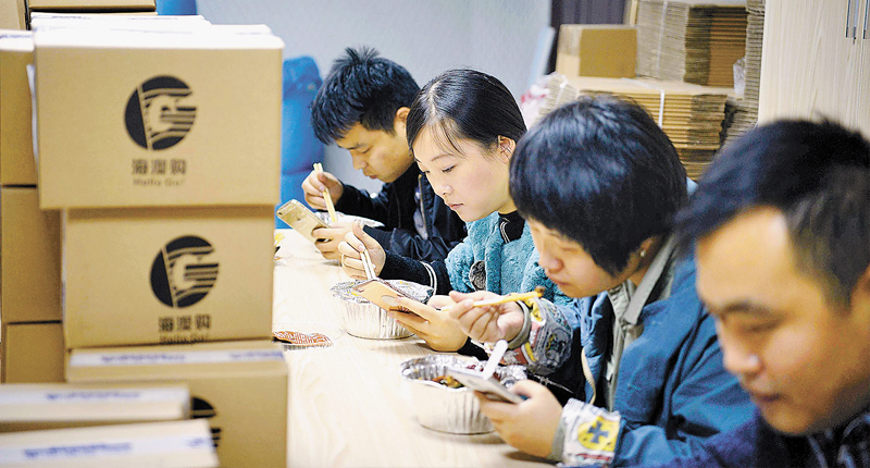 某電商員工邊吃飯邊看手機上的訂單。(中新社資料照片)