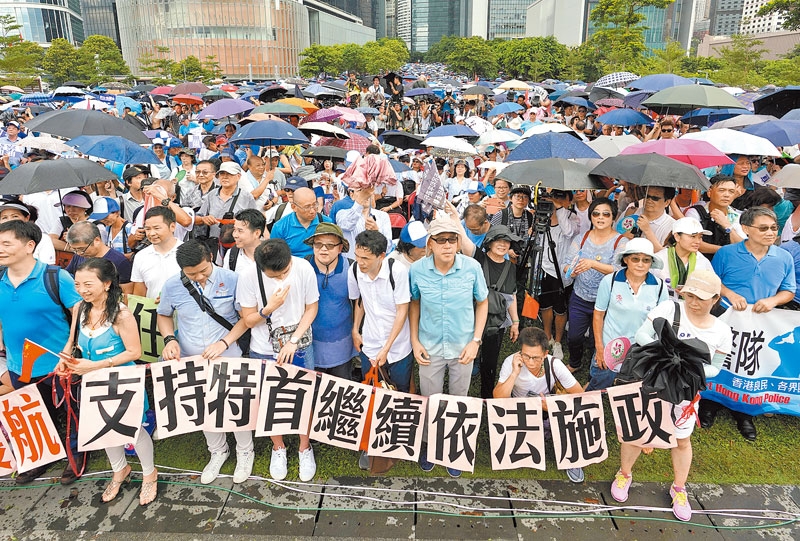 6月30日,香港市民在大雨中聲援香港警察,在集會現場打出「支持特首繼續依法施政」的布條。(中新社)