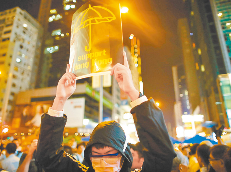 香港反修例運動延燒,情勢較2014年雨傘運動嚴峻。圖為2014年香港雨傘運動,旺角集會者手舉宣傳標語。(中新社資料照片)