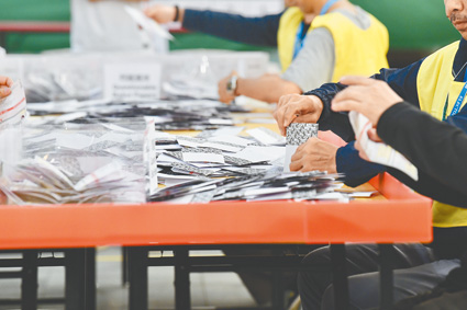 ▲11月24日晚上,香港區議會投票結束後,位於九龍塘官立小學點票站的工作人員在點票時,現場有不少市民圍觀。(中新社)