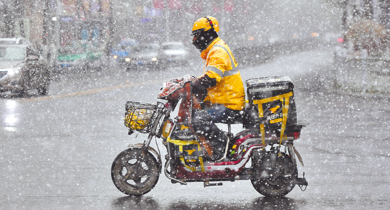 10月31日,在青海省西寧市,一名外賣配送員在雪中騎行。(新華社)