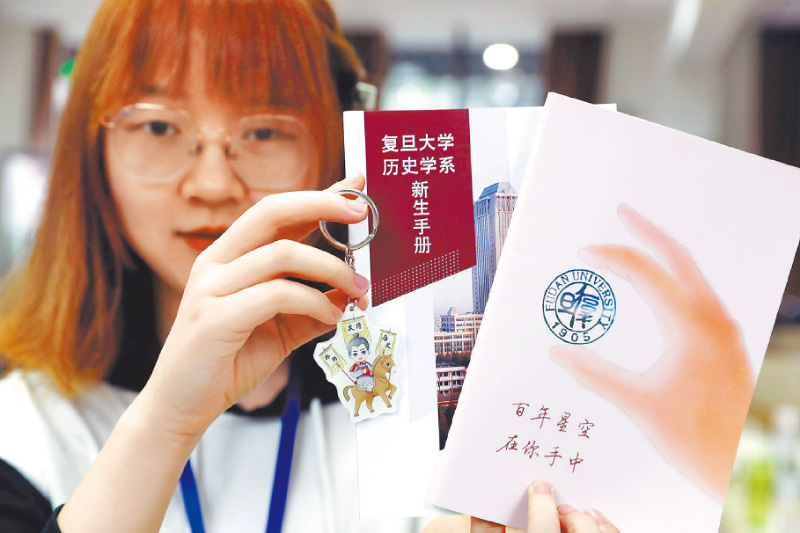 復旦章程修改惹議,凸顯學術自由受限,圖為2019年復旦迎新,一名學生展示新生手冊。(新華社資料照片)