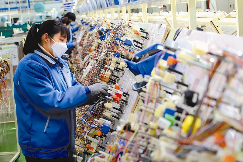 2月26日,山東省青島西海岸新區一家企業員工在生產線上製作汽車線束。(新華社)