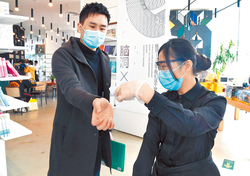 北京一書店近期恢復營業,工作人員為入內讀者測量體溫及檢查健康碼。(新華社)