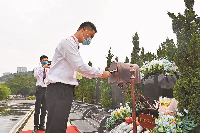 3月26日,廣西南寧市青龍崗長安墓園內,生命禮儀師進行代客祭掃服務,並透過手機向客戶展示。(中新社)