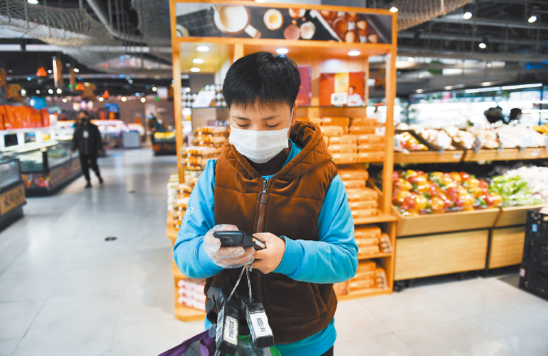2月14日,盒馬鮮生北京十里堡店的員工在查看外送訂單信息,準備揀貨。(新華社)