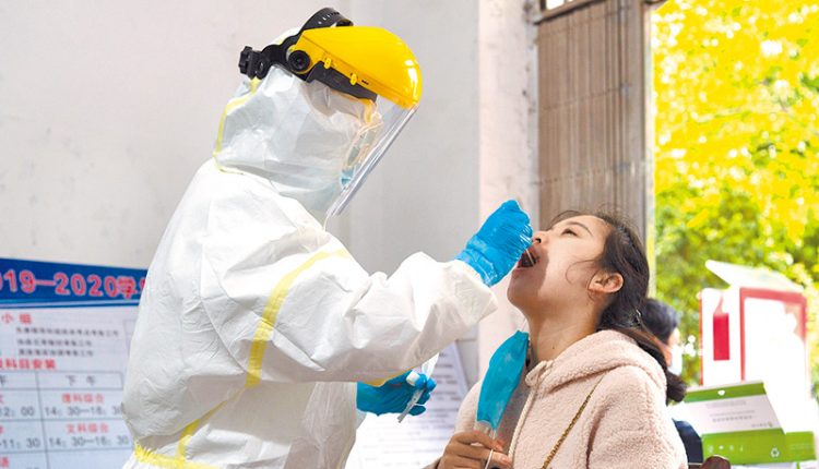 4月18日，湖北一檢測點內，工作人員在為民眾做核酸檢測。（新華社）