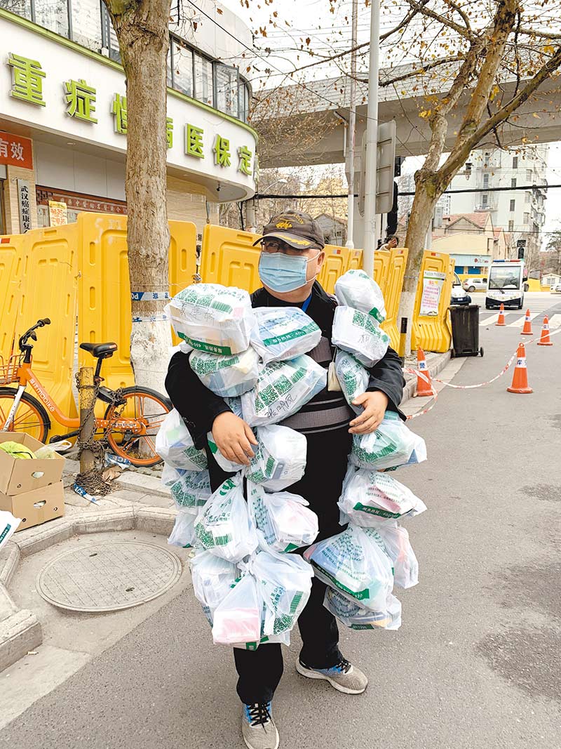 2月24日,武漢市一社區網格員,把為居民購買的藥掛在身上。 (新華社)