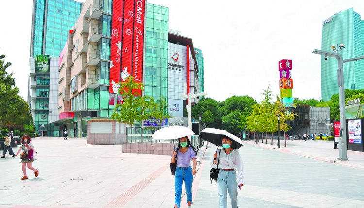 6月8日，北京市中關村步行街，行人用遮陽傘遮擋陽光。（新華社）