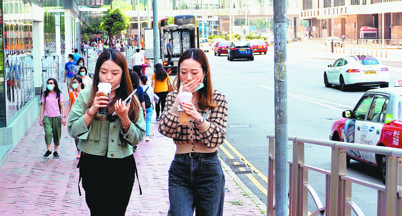 香港天氣炎熱,街上行人脫下口罩喝凍飲消暑。(中新社資料照片)
