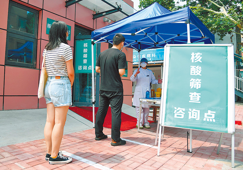 6月20日,北京開展大規模核酸檢測 ,醫護人員在為市民介紹核酸檢測採樣流程。(新華社)