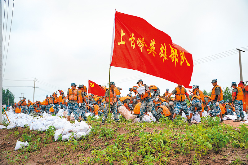 7月13日,解放軍中部戰區官兵裝填沙土石,加固湖北沙套湖子堤。(新華社)