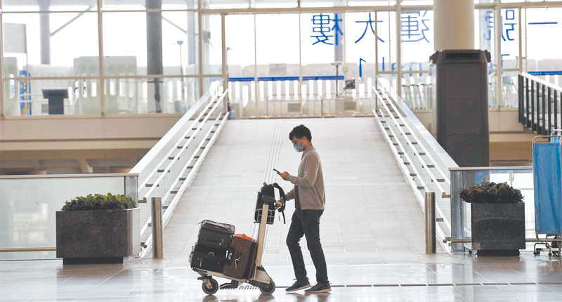 8月13日,香港機場人潮稀疏,一名戴口罩旅客獨自推行李。(中新社)